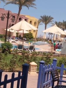 a blue fence in front of a pool with umbrellas at ساوث بيتش بورتو السخنه in Ain Sokhna