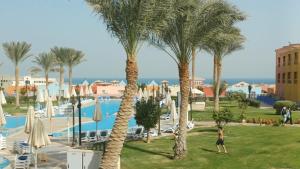 a person standing between two palm trees near a pool at ساوث بيتش بورتو السخنه in Ain Sokhna