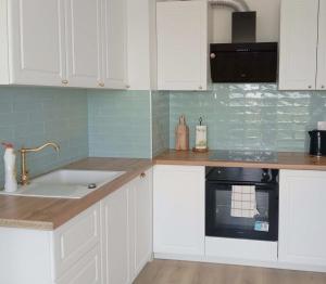 a kitchen with white cabinets and a sink at Kawalerka pod lasem in Poddębice