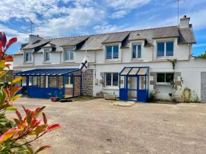 a large white house with blue doors and windows at Le Bercail in Plouézec
