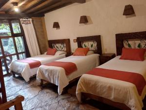 a bedroom with three beds in a room at Hotel Hacienda Don Juan in San Cristóbal de Las Casas