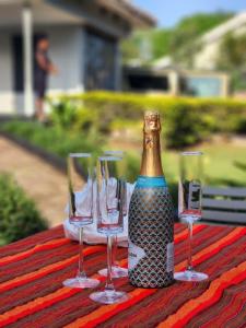a bottle of champagne and three wine glasses on a table at JOSIRE Residence in Entebbe