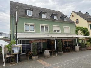 a green building with tables and chairs in front of it at Gutsweinschänke & Pension Müllers in Kröv