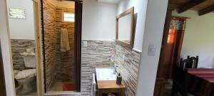 a bathroom with a glass shower with a brick wall at Cálida Casa con amplio espacio verde en Raco in Raco +20 photos