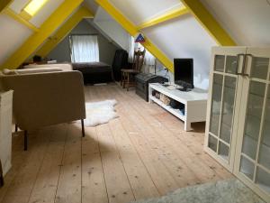 a living room with a couch and a desk with a television at B & B Zazza in Rauwerd