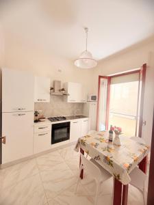 a white kitchen with a table and a window at Home Sisters in Trapani