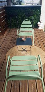 a green bench and a table on a deck at Chambre avec grande terrasse privative in Aurillac