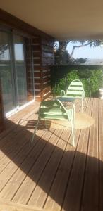 a green chair and a table on a deck at Chambre avec grande terrasse privative in Aurillac
