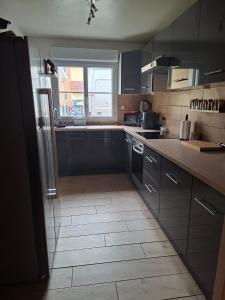 a kitchen with black cabinets and a large window at Résidence Le Soleil de Nousty in Nousty