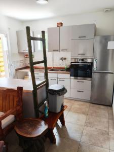 a kitchen with white cabinets and a wooden chair at Villa proche plage pour 3 pers in Vielle-Saint-Girons
