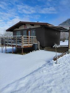 a house with a deck in the snow at Chalet a la montagne in Cornod