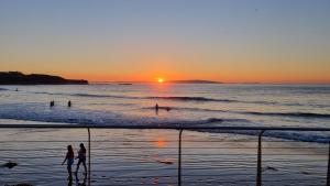 people playing in the water at the beach at sunset at Causeway Rooms in Ballybogy +10 photos