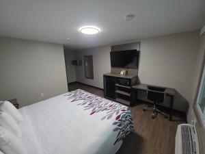 a hotel room with a bed and a desk and a television at Red Roof Inn Sutton in Sutton