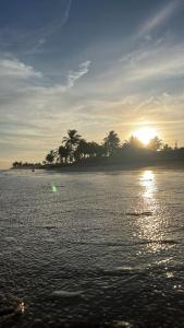 a sunset over a body of water with trees in the background at Caueira Beach House in Itaporanga dʼAjuda