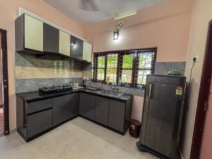 a kitchen with a black counter and a refrigerator at Kattuvallil AGAPE Homestay 4B2HK in Thiruvalla