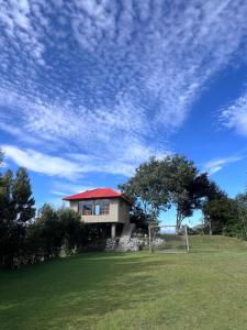 a house with a red roof on a grass field at Refugio del venado Cuicocha in Cotacachi