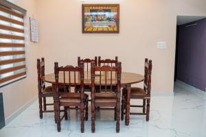 a dining room with a table and chairs at Kattuvallil AGAPE Homestay 4B2HK in Thiruvalla +7 photos