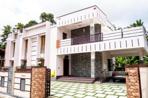 a white house with a balcony and a driveway at Kattuvallil AGAPE Homestay 4B2HK in Thiruvalla