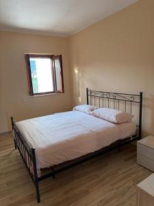 a bedroom with a large bed with white sheets and a window at Vale house in Monte San Biagio