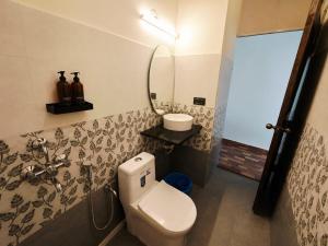 a bathroom with a toilet and a sink and a mirror at Coco Nest Mandrem in Mandrem
