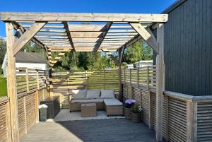a wooden pergola with a couch on a deck at Three bedrooms house in Holmestrand