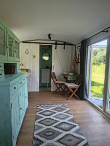 a kitchen with green cabinets and a table with a rug at Tiny House Zagroda Kopytkowo in Ropica Górna