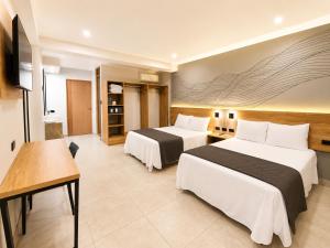 ein Hotelzimmer mit zwei Betten und einem Fernseher in der Unterkunft Senoma Hotel - Adults only in Ica