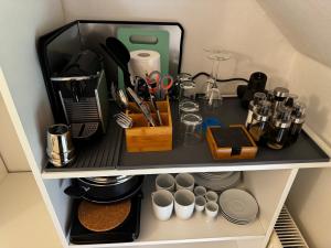 a shelf with kitchen utensils and cups on it at Jade Villa an der Nordsee in Jaderaltendeich