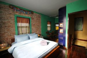 a bedroom with a large white bed with a brick wall at Baan Nai Nakhon in Songkhla