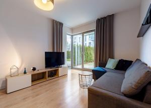a living room with a couch and a tv at Lighthouse Apartment Nadmorze - 150 m od morza, ogródek, garaż in Gdańsk