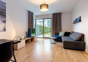 a living room with a couch and a television at Lighthouse Apartment Nadmorze - 150 m od morza, ogródek, garaż in Gdańsk