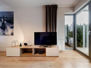 a living room with a tv and a large window at Lighthouse Apartment Nadmorze - 150 m od morza, ogródek, garaż in Gdańsk