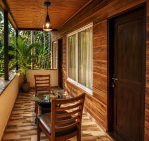 a porch with two chairs and a glass table at Coco Nest Mandrem in Mandrem