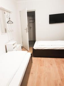 2 Betten in einem weißen Zimmer mit Holzböden in der Unterkunft KWATERY KALINA-DUSZKA HOSTEL in Płock