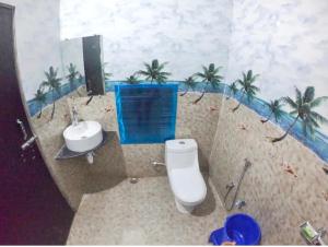 a bathroom with a toilet and a sink and palm trees at Hotel A3cube in Panna +16 photos