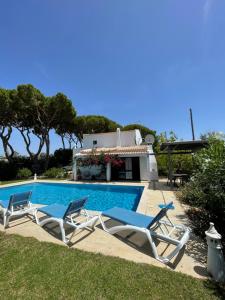 two lounge chairs and a swimming pool in front of a house at Vila Estrela in Vale do Lobo