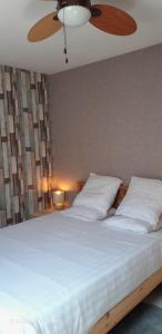 a bedroom with a large white bed with a ceiling fan at Suite-Appart Beau Soleil - 24H Le Mans Métropole in Allonnes