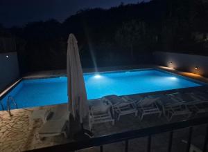 a swimming pool with chairs and an umbrella at night at MostOliva luxury Rooms in Pržno +4 photos