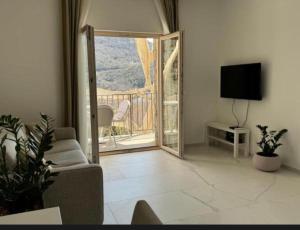 a living room with a couch and a television and a balcony at MostOliva luxury Rooms in Pržno