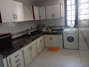 a kitchen with white cabinets and a washing machine at Villa pieds dans l'eau Cabo in Cabo Negro