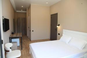 a bedroom with a white bed and a table and a chair at Mn Hotel Borjomi in Borjomi
