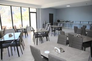 a dining room with tables and chairs and windows at Mn Hotel Borjomi in Borjomi