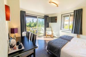 a bedroom with a desk and a bed and a table with a desk at Logis Clair Matin Resort & Spa in Le Chambon-sur-Lignon +22 photos