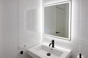 a white bathroom with a sink and a mirror at Formentera Suite 3 in Es Pujols