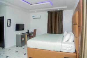a bedroom with a bed and a desk and a television at Wiztk suites in Sangotedo