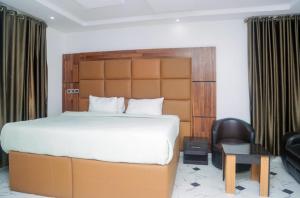 a bedroom with a large bed and a chair at Wiztk suites in Sangotedo