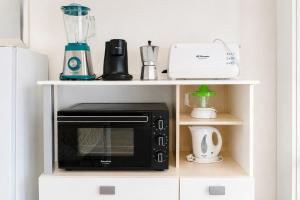 a black microwave on a white shelf in a kitchen at Formentera Suite 3 in Es Pujols +16 photos