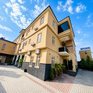 a yellow building with windows on a brick driveway at Wiztk suites in Sangotedo