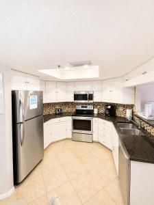 a kitchen with white cabinets and a stainless steel refrigerator at Beach Palms- Unit 102 in Clearwater Beach