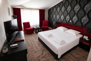 a bedroom with a large white bed and red chairs at Hotel Baia Rosie Resort in Slănic